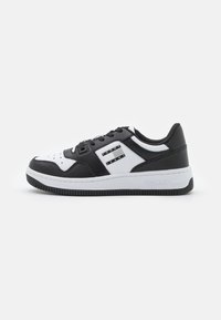 Sneakers basse in bianco e nero con tomaia in pelle, punta perforata e suola in gomma; presentano accenti con logo e dettagli testurizzati sui lati.