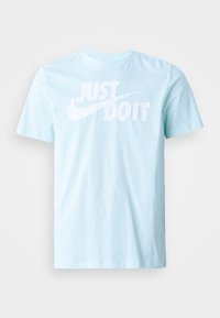 Šviesiai mėlyna medvilninė marškinėliai su apvalia kaklo iškirpte, kuriuose ryškiai baltu tekstu užrašyta "JUST DO IT" ir Nike swoosh logotipas, lygi tekstūra.