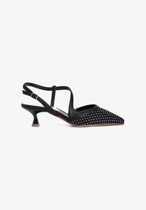 Scarpa nera con tacco alto e allacciatura alla caviglia, punta appuntita, tessuto testurizzato con pois bianchi e tacco a blocco in contrasto.