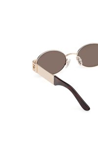 Ovaaliset aurinkolasit, joissa on ruskeat linssit, kultaväriset metallikehykset ja ruskea kilpikonnakuosiset varret. Varusteena säädettävät nenäpaddit mukavuutta varten.