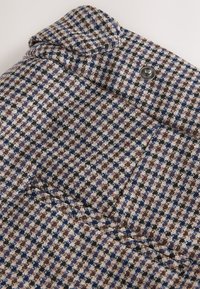 Wool-blend jacket in a patterned fabric featuring blue, brown, and black checks, with a notch lapel and silver button detail.