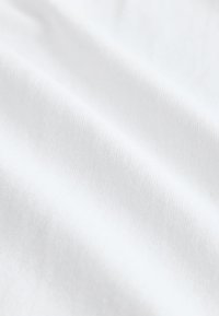 Gros plan sur un tissu blanc lisse avec des plis doux et une texture fine visible.
