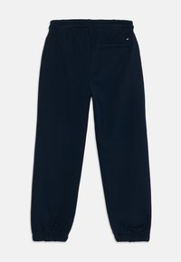 Calças de sweat azul marinho com cintura elástica, punhos elásticos e um bolso traseiro com um pequeno detalhe de logótipo. Tecido suave e macio.