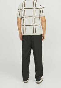 Kortärmad tröja för män i ljusgrått med brunt rutmönster, tillsammans med svarta byxor. Slät textur, avslappnad passform och ribbad nederkant.