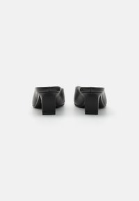 Mule-uri din piele neagră cu toc pătrat. Textură netedă, design cu spatele deschis și formă minimalistă. Fără modele vizibile sau accente de metal.