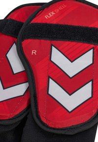 Rote und schwarze Schutzausrüstung mit der Aufschrift „FLEX SHELL“ mit weißen Chevron-Mustern und einem schwarzen Klettverschluss zum Befestigen.