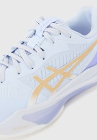 Light blue running shoe with a mesh upper, golden logo, textured design, and cushioned sole in white and lavender accents.