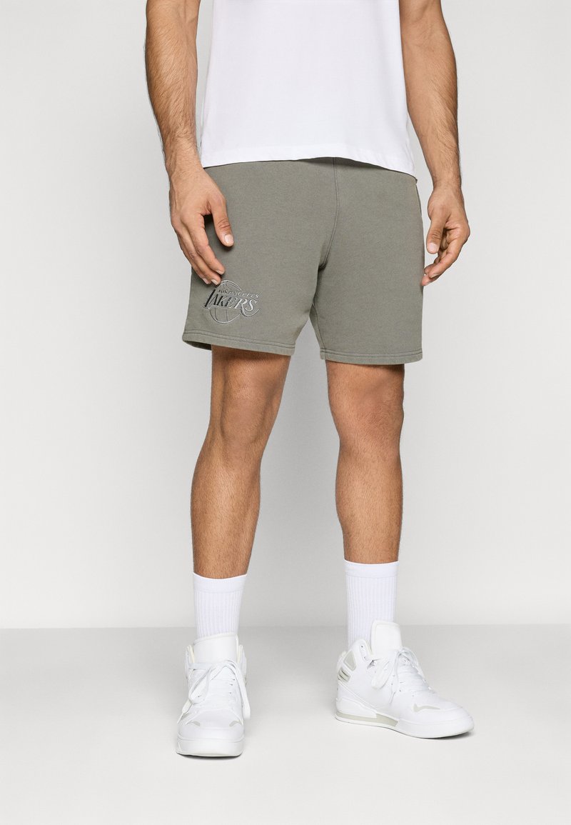 Bermuda cinza de algodão com um logótipo dos "Los Angeles Lakers". Combinada com meias desportivas brancas e sapatilhas brancas sobre um fundo neutro.