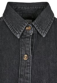 Svart denimskjorte med spiss krage, to brune knapper og subtil tekstur. Merke synlig inne i kragen.