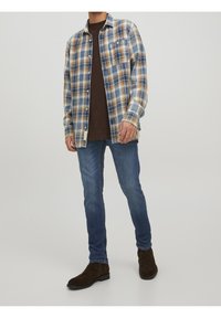 Blå och beige rutig skjorta i bomull, långärmad, knäppning fram, kombinerad med mörka jeans och bruna mockastövlar.