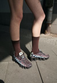 Nike shoes with a brown and blue gradient design, featuring a textured upper and bubble-like sole. Paired with brown socks.