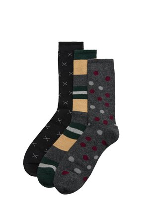 Tres pares de calcetines: negros con patrón de cruces blancas, amarillos con rayas verdes y grises con puntos rojos y grises, todos de longitud media hasta la pantorrilla.