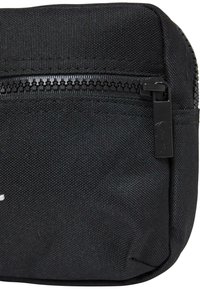 Zwarte stoffen tas met een gestructureerd oppervlak, voorzien van een zwarte rits en een kleine ritstrekkker. Compact ontwerp, geschikt voor het dragen van kleine voorwerpen.