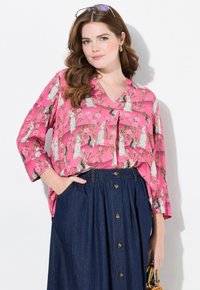 Blusa rosa con motivo floreale e animale, scollatura a V, vestibilità ampia, maniche a tre quarti, abbinata a una gonna in denim scuro con bottoni.