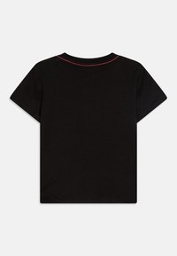 T-shirt en coton noir à manches courtes, avec un col rond et des coutures rouges le long des coutures des épaules.