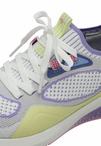 Kevyt urheilujalkine harmaasta neuloksesta, jossa on valkoiset nauhat, pastellsävyt vaaleanpunaisena, purppurana ja vihreänä sekä teksturoitu pohja.