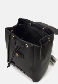Czarna skórzana torba typu bucket z teksturowaną powierzchnią, złotymi oczkami, wiązaniem na sznurek i akcentem z logo. Otwarty top odsłaniający wewnętrzną kieszeń.