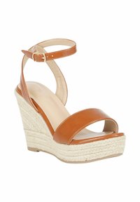 Sandali con tacco wedge in pelle marrone, con un tacco in juta intrecciata, dotati di due fasce larghe e una cinghia alla caviglia con chiusura a fibbia.