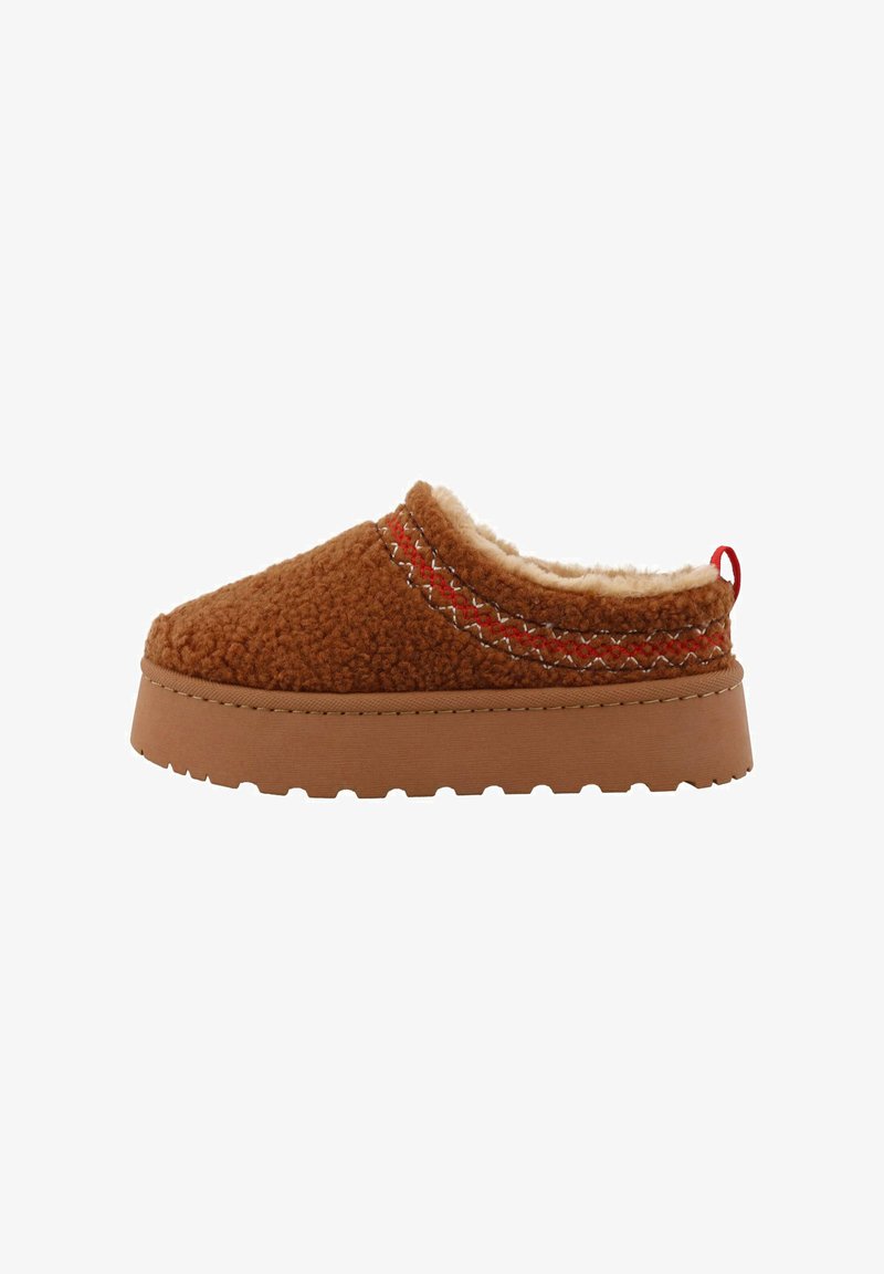 Brązowe buty slip-on z owczej skórki z teksturowanym wierzchem, kontrastującym czerwonym przeszyciem i grubą gumową podeszwą dla lepszej przyczepności. Posiadają pętelkę z tyłu.