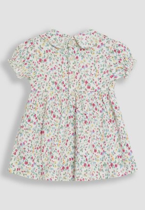 Kukkamekossa on pehmeä, kevyt kangas, jossa on lyhyet puffihihat, pyöreä kaulus ja nappikiinnitys takana. Monivärinen kukkakuosi.