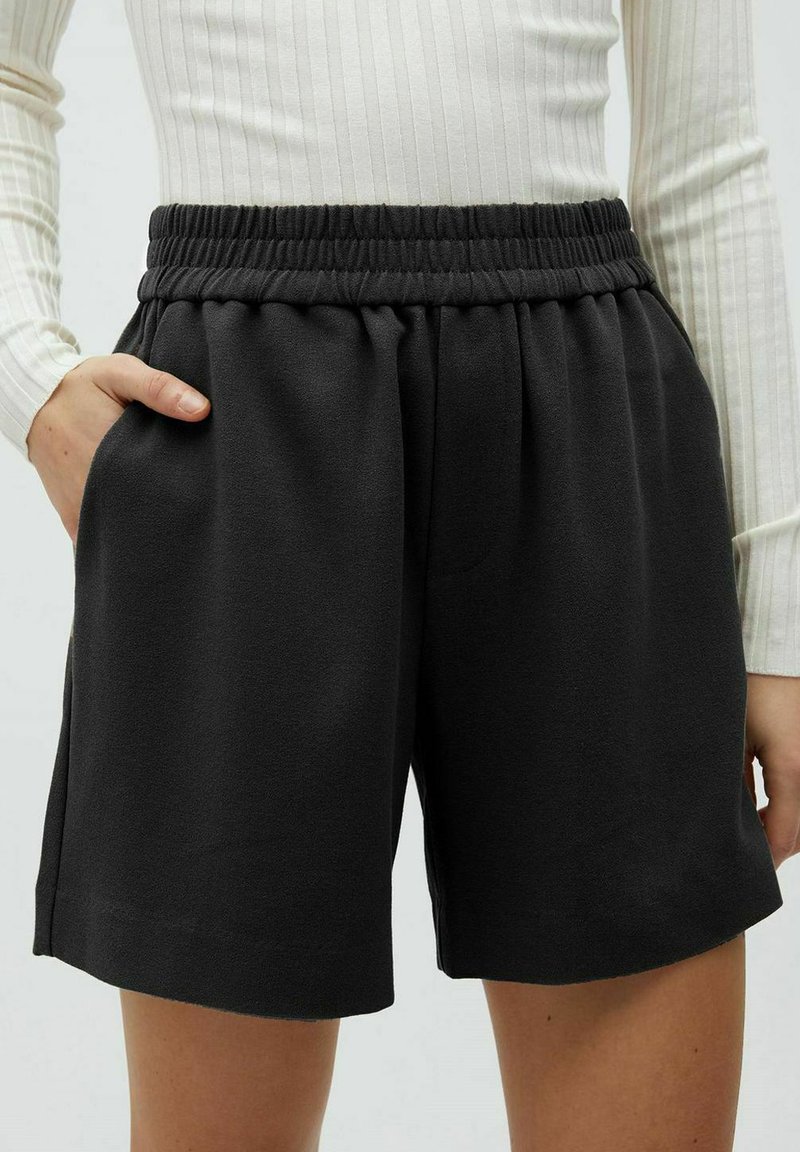 Zwarte, ontspannen shorts met een elastische tailleband en zijzakken, gemaakt van een zachte stof met een gladde textuur.