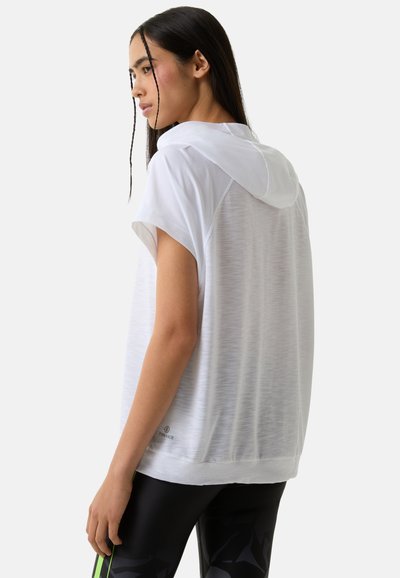 White short-sleeve hoodie with a drawstring, made of lightweight textured fabric, paired with black leggings featuring green accents.