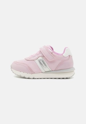 Baskets roses pour enfant avec semelle blanche, bande latérale blanche et argentée et une seule bride Velcro sur fond clair.