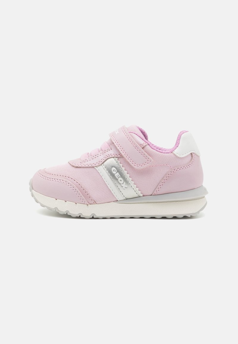 Baskets roses pour enfant avec semelle blanche, bande latérale blanche et argentée et une seule bride Velcro sur fond clair.