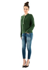 Pull vert en maille avec un col henley et des boutons blancs, associé à un jean bleu clair ajusté et des talons noirs.