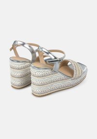 Sandalias de cuña metálicas plateadas con plataforma de cuerda trenzada y hilos de colores decorativos. Correa para el tobillo ajustable y diseño de punta redondeada.