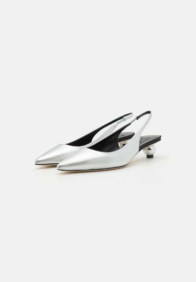 Zapatos plateados metálicos tipo slingback con punta afilada y tacón geométrico bajo. Presentan un diseño elegante y forro interior negro.