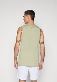 Light green sleeveless athletic tank top with a round neckline and stitched detailing. Features a logo at the back and flat hem.