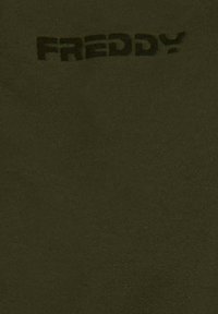 Tejido verde oliva de textura suave con la palabra "FREDDY" impresa en negro. El diseño es sencillo y minimalista, sin patrones adicionales.
