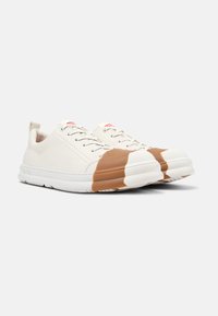 White sneakers made of smooth fabric with a brown rubber toe cap. Features round white sole and thin laces, with a loop at the heel.