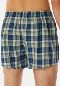 Boxer shorts pour hommes au motif écossais, présentant des couleurs vert, bleu marine et bleu, avec une taille élastique et un tissu léger.