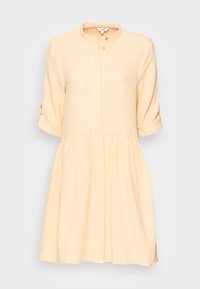 Light peach short-sleeve dress with a buttoned collar, cinched waist, and a flared skirt. Soft, textured fabric with a subtle grid pattern.