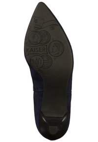 Semelle de chaussure à talon haut en daim bleu marine avec des motifs en relief détaillés, y compris des pièces de monnaie et du texte. Sections de talon et de bout en caoutchouc noir lisse.