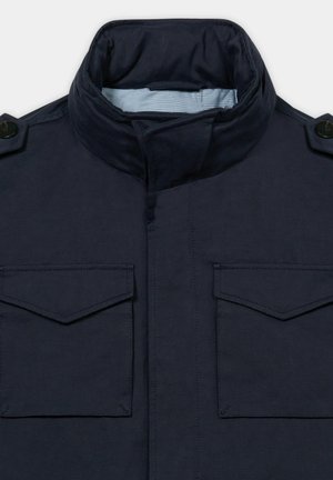 Dunkelblaue Jacke mit hohem, gepolstertem Kragen, zwei vorderen Klappentaschen und mit Knöpfen versehenen Schulterklappen, gefüttert mit hellblau kariertem Stoff.