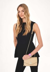 Fekete peplum felső, testhezálló fazon; karcsú fekete nadrág. Krém színű keresztpántos táska láncos pánttal, rózsaszín óra ezüst díszítéssel.