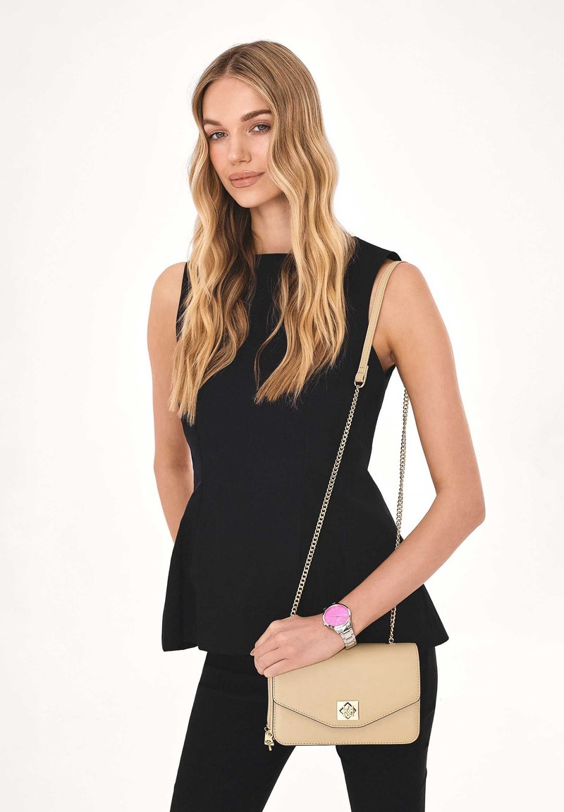 Fekete peplum felső, testhezálló fazon; karcsú fekete nadrág. Krém színű keresztpántos táska láncos pánttal, rózsaszín óra ezüst díszítéssel.