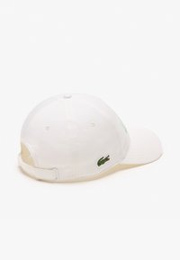Gorra de béisbol blanca de algodón con logo de cocodrilo bordado en verde, correa ajustable en la parte posterior, diseño estructurado y textura suave.
