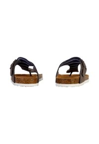 Bruine sandalen met kurken voetbed, platte witte zool en verstelbare gestreepte banden. De achterkant toont een uitsnijdontwerp en hardwareaccenten.