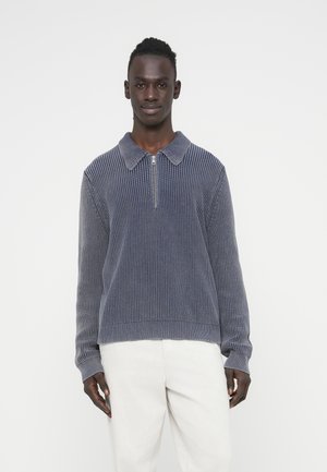 Sweter typu pulower z ciemnoniebieskiej, prążkowanej tkaniny, z kołnierzem na zamek, długimi rękawami i dopasowanym pasem w talii. Materiał o średniej grubości i fakturowanej powierzchni.