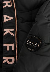 Čierna puffa bunda s veľkým nápisom "BAKER" v svetloružovej farbe, s okrúhlym logom na rukáve so zlatým textom a akcentmi.