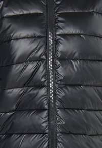 Giacca a vento nera con design trapuntato, strisce orizzontali, zip centrale e texture lucida e liscia.