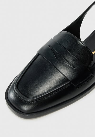 Mocassino in pelle nera con texture liscia, punta squadrata e dettagli del cucito superiore in rilievo. Presenta un retro aperto per una facile calzata.