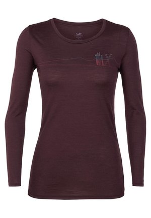 Chemise ajustée à manches longues en laine mérinos violet foncé avec un motif brodé subtil de montagne et de bâtons de ski sur la poitrine.