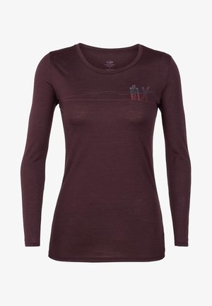 Chemise ajustée à manches longues en laine mérinos violet foncé avec un motif brodé subtil de montagne et de bâtons de ski sur la poitrine.