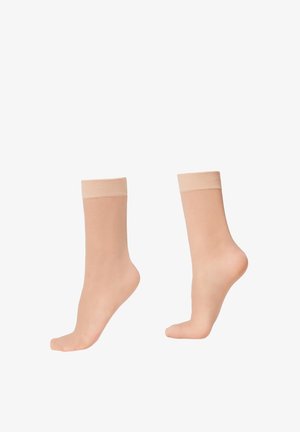 Dos calcetines tobilleros beige transparentes mostrados en maniquíes de pie transparentes, uno con el pie plano y otro de puntillas, contra un fondo blanco.