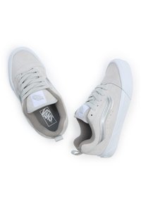 Jasnoszare zamszowe sneakersy z białymi gumowymi podeszwami, z srebrnymi paskami po bokach, okrągłymi sznurówkami oraz wyściełanym kołnierzem dla wygody.